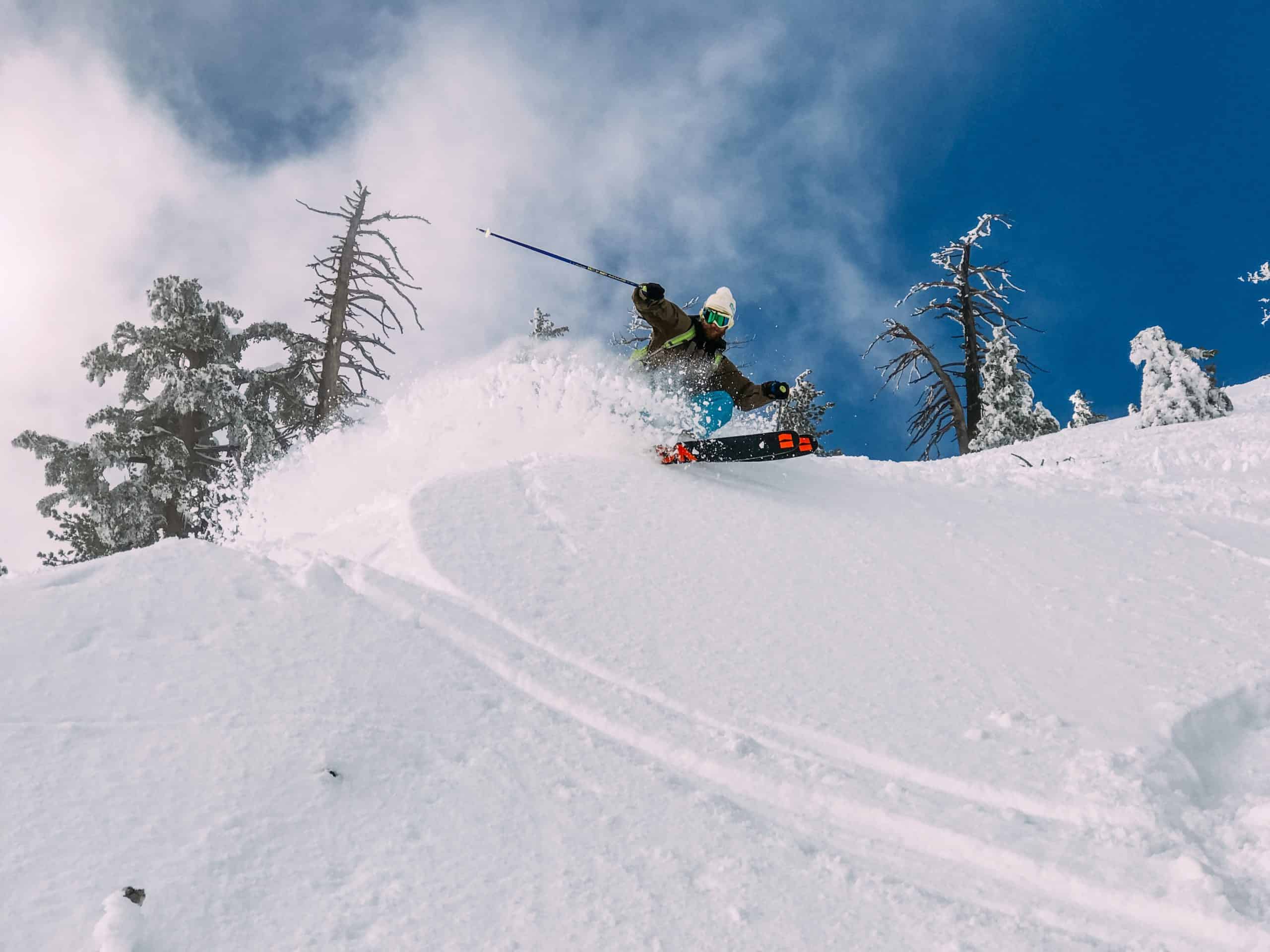 A man slashing powder while skiing in a sunny day
