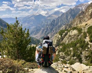 man sitting by mountains with hiking pack